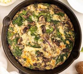 easy egg white frittata fluffy high protein, A spinach and mushroom egg white frittata baked in a black skillet garnished with cheese and herbs Surrounding the skillet are a fork small bowls of cheese mushrooms and fresh spinach leaves on a white surface