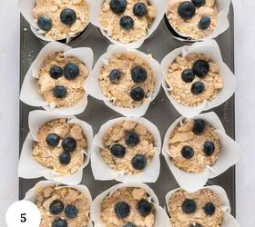blueberry yogurt muffins with crumble topping, A muffin tray lined with white parchment paper holds twelve unbaked blueberry yogurt muffins topped with streusel and fresh blueberries A white circle with the number 5 is in the lower left corner