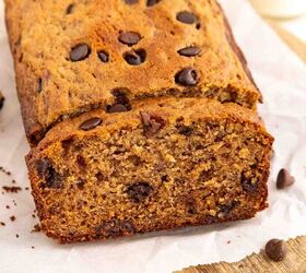 chocolate chip banana bread ultra moist easy, A loaf of banana bread with chocolate chips sits on parchment paper atop a wooden board One slice has been cut revealing a moist dense texture with chocolate chips throughout