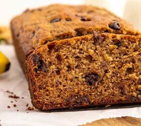 chocolate chip banana bread ultra moist easy, A close up of a sliced loaf of banana bread with visible chocolate chips resting on parchment paper atop a wooden surface The bread looks moist and golden brown