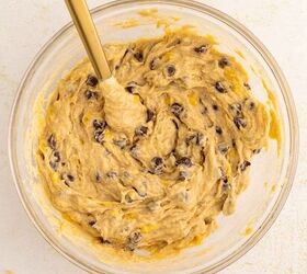 chocolate chip banana bread ultra moist easy, A glass bowl filled with chocolate chip banana bread dough and a gold spoon resting inside on a light colored surface