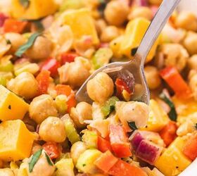 easy buffalo chickpea salad quick meal prep friendly, Close up of buffalo chickpea salad in a bowl with a spoon lifting a portion showing chickpeas diced vegetables and cheddar cheese coated in a glossy buffalo dressing