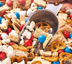 easy red white blue snack mix 4th of july no bake recipe, Hand scooping red white and blue snack mix from a bowl with popcorn pretzels and M M s for 4th of July party