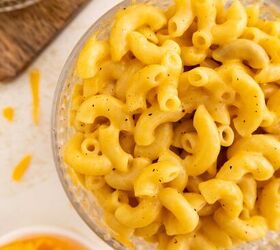 microwave mac and cheese, A close up of a bowl filled with creamy macaroni and cheese with elbow shaped pasta coated in a rich yellow cheese sauce Shredded cheese and a cloth napkin are visible in the background