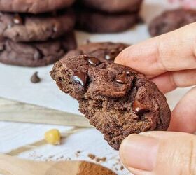 flourless chocolate chickpea cookies, Flourless chocolate cookies with chunks of chocolate A hand holding a half eaten cookie A spoon of cinnamon is sitting in front of the image