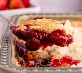3 ingredient strawberry dump cake the easiest dessert you ll make, Strawberry Dump Cake with a serving spoon scooping and hovering above the pan