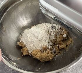 easy no bake cookie dough bark edible safe to eat, A close up of hands using an electric hand mixer to blend flour into cookie dough in a large stainless steel mixing bowl on a gray countertop