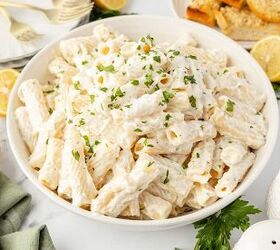 lemon ricotta pasta without heavy cream, A large white bowl filled with creamy rigatoni pasta garnished with chopped parsley Slices of lemon garlic bread plates and a wooden spoon are visible around the bowl on a white surface