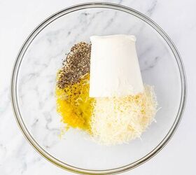lemon ricotta pasta without heavy cream, A glass bowl on a marble surface contains ricotta cheese shredded parmesan cheese lemon zest and ground black pepper in separate piles