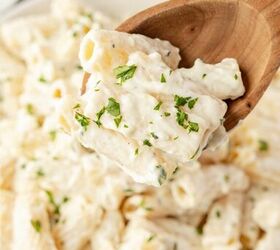 lemon ricotta pasta without heavy cream, A wooden spoon holds a serving of creamy rigatoni pasta topped with chopped parsley above a bowl filled with more of the same pasta A blurred lemon wedge and bread are in the background