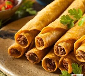 air fryer taquitos how to make taquitos in an air fryer, CLose up image of air fryer taquitos stacked on a plate with cilantro and salsa in the background