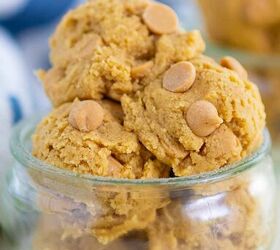 edible peanut butter cookie dough no eggs no bake, A small glass jar is filled with scoops of peanut butter cookie dough each scoop studded with peanut butter chips The jar sits on a light surface and there are more scoops blurred in the background