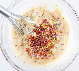 easy birthday cake mini muffins with sprinkles, Rainbow sprinkles added to birthday cake mini muffin batter in a glass bowl