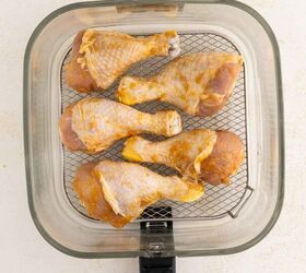 air fryer chicken legs crispy juicy and easy, Six seasoned chicken drumsticks arranged in a single layer inside an air fryer basket ready to be cooked The basket has a metal mesh bottom and is viewed from above
