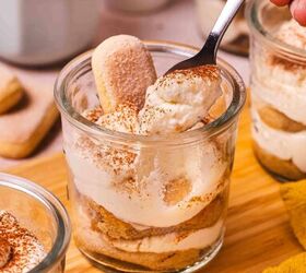 the best no bake tiramisu cheesecake cups mini dessert in jars, Spoon scooping creamy layered no bake tiramisu cheesecake cup from a mini glass jar showing mascarpone cream and coffee soaked layers
