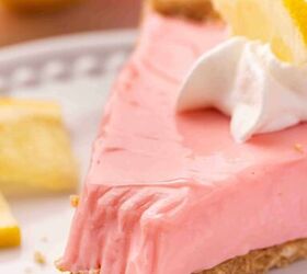 the only no bake pink lemonade pie you ll ever need, Close up of a creamy pink lemonade pie slice with fluffy whipped cream and a lemon slice garnish