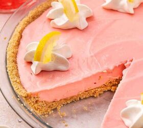 the only no bake pink lemonade pie you ll ever need, Inside view of a chilled pink lemonade pie after one slice is removed revealing the smooth dense creamy pink filling over a buttery graham cracker crust