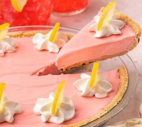 the only no bake pink lemonade pie you ll ever need, A slice of no bake pink lemonade pie being lifted from a pie dish showing the thick golden graham cracker crust and creamy pink filling