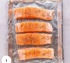 pistachio crusted salmon with lemon and za atar, Four raw salmon fillets ideal for making pistachio crusted salmon are seasoned with salt and pepper and arranged in a row on a foil lined baking sheet ready for cooking