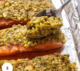 pistachio crusted salmon with lemon and za atar, A spoon spreads a chunky greenish pistachio crust over raw salmon fillets creating delicious pistachio crusted salmon on a foil lined baking tray A white circle with the number 3 appears in the corner