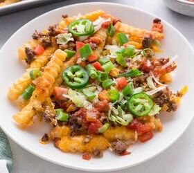 nacho fries with ground beef easy 30 minute recipe, A plate of crinkle cut fries topped with melted cheese ground beef chopped tomatoes green onions shredded lettuce sliced jalape os and salsa A green and white towel and a tray are visible nearby