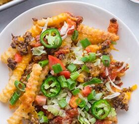 nacho fries with ground beef easy 30 minute recipe, A plate of crinkle cut fries topped with melted cheese ground beef diced tomatoes shredded lettuce sliced jalape os and chopped green onions with salsa and more fries in the background