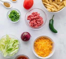 nacho fries with ground beef easy 30 minute recipe, Assorted ingredients for nacho fries including crinkle cut fries ground beef shredded cheddar salsa lettuce green onion red onion tomato jalape o oil spices and salt and pepper arranged on a white surface