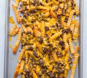 nacho fries with ground beef easy 30 minute recipe, A baking sheet topped with crinkle cut French fries cooked ground beef and melted cheddar cheese creating a loaded fries dish