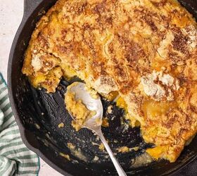 easy 3 ingredient peach dump cake in a cast iron skillet, Skillet with half of the peach dump cake and a metal spoon