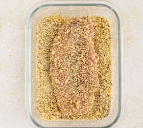 baked parmesan crusted chicken better than fried, A raw chicken breast coated in breadcrumbs sits in a rectangular glass dish on a light colored surface