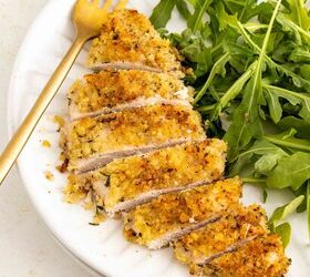 baked parmesan crusted chicken better than fried, A white plate with sliced breaded baked chicken breast and a serving of fresh arugula a gold fork rests on the plate