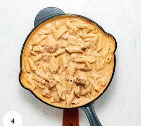 garlic parmesan pasta with chicken, A skillet filled with creamy garlic parmesan pasta with chicken tender penne and juicy pieces of chicken in a rich orange tinted sauce sits on a white surface A wooden handle extends from the pan A circular label with the number 4 is in the lower left corner