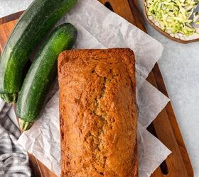 einkorn zucchini bread, Zucchini bread loaf on parchment with whole zucchinis shredded zucchini and butter nearby
