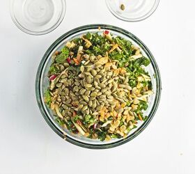 easy kale apple salad with lemon miso dressing, Kale salad tossed with dressing and topped with pumpkin seeds and raisins before serving