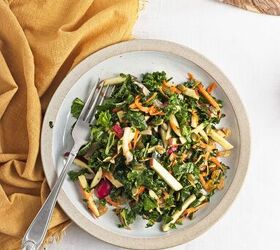 easy kale apple salad with lemon miso dressing, Single serving of kale apple salad on a plate with apples carrots radishes pumpkin seeds and raisins