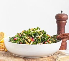 easy kale apple salad with lemon miso dressing, Side view of kale apple salad in a white serving bowl with homemade lemon miso dressing nearby