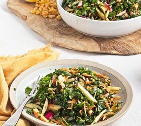 easy kale apple salad with lemon miso dressing, Served kale apple salad on a plate with fresh apples carrots radishes pumpkin seeds and raisins