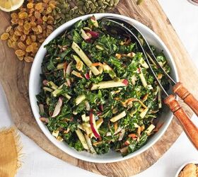 easy kale apple salad with lemon miso dressing, Kale apple salad with apples carrots radishes pumpkin seeds and raisins tossed in lemon miso dressing and served in a large white bowl