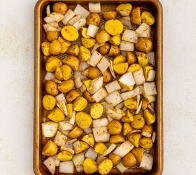 crispy roasted potatoes and onions, A baking sheet filled with chopped yellow potatoes and diced onions seasoned and ready to roast sits on a light colored surface