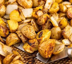 crispy roasted potatoes and onions, A baking sheet filled with roasted potato pieces and onions seasoned and browned with a metal spatula lifting some of the vegetables