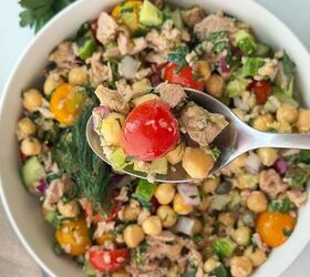 mediterranean chickpea tuna salad no mayo, A spoonful of chickpea tuna salad with cherry tomatoes cucumber red onion herbs and parsley is held above a bowl containing the same colorful salad