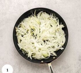 greek yogurt french onion dip with real caramelized onions, Sliced onions are spread evenly in a black frying pan on a light gray surface ready to be slowly caramelized as the first step in making a delicious greek yogurt french onion dip A white circle with the number 1 is at the bottom left corner