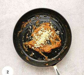 greek yogurt french onion dip with real caramelized onions, A black pan with a brown sauce and chopped garlic on top reminiscent of the rich flavors found in greek yogurt french onion dip sits on a light gray surface A white circle with the number 2 is in the lower left corner