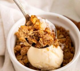 air fryer apple crisp, A spoonful of apple crisp hovers over a white ramekin filled with more apple crisp and a scoop of vanilla ice cream