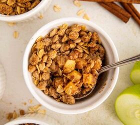 air fryer apple crisp, Mini apple crisps with oat topping in ramekins one with a spoon inside served with vanilla ice cream Green apple slices and cinnamon sticks are nearby on a white surface