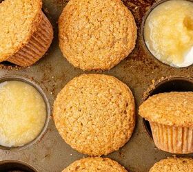 moist applesauce muffins, A close up of several golden brown muffins in a muffin tin with two cups filled with applesauce instead of muffins Some muffins are slightly tilted or out of their cups