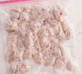 garlic butter chicken bites ready in 20 minutes, A clear ziplock bag filled with uncooked flour coated chicken pieces arranged in a single layer on a white marble surface