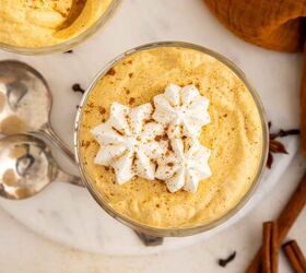 creamy pumpkin mousse easy no bake, A glass of creamy pumpkin mousse topped with whipped cream and a sprinkle of cinnamon with a spoon cinnamon sticks and cloves nearby on a marble surface