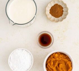 creamy pumpkin mousse easy no bake, Five recipe ingredients on a white surface a measuring cup of milk a small dish of brown spice a bowl of orange pumpkin puree a bowl of white powder and a small glass container with dark liquid