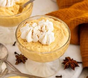 creamy pumpkin mousse easy no bake, A glass dish filled with creamy orange pumpkin mousse topped with whipped cream and sprinkled with cinnamon surrounded by star anise cloves spoons and an orange napkin